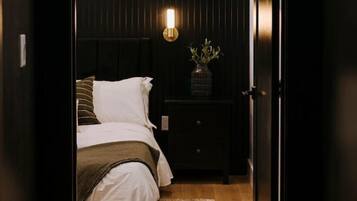 A bedroom with a bed, bedside table, lamp, and a dark wooden wardrobe.