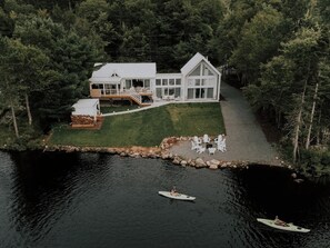 Une propriété au bord du lac, comprenant une grande maison, un quai et un petit bateau.