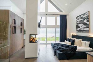 Une chambre moderne avec un lit, une cheminée et une grande fenêtre donnant sur un beau paysage.
