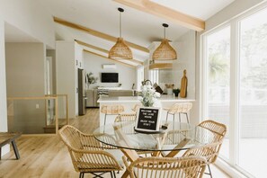 A modern kitchen with a dining area, wicker furniture, and a welcome sign.