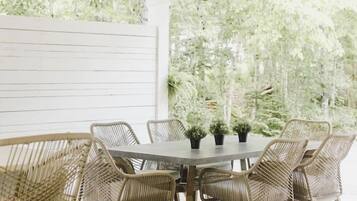 An outdoor patio with a wooden table and wicker chairs, surrounded by string lights.