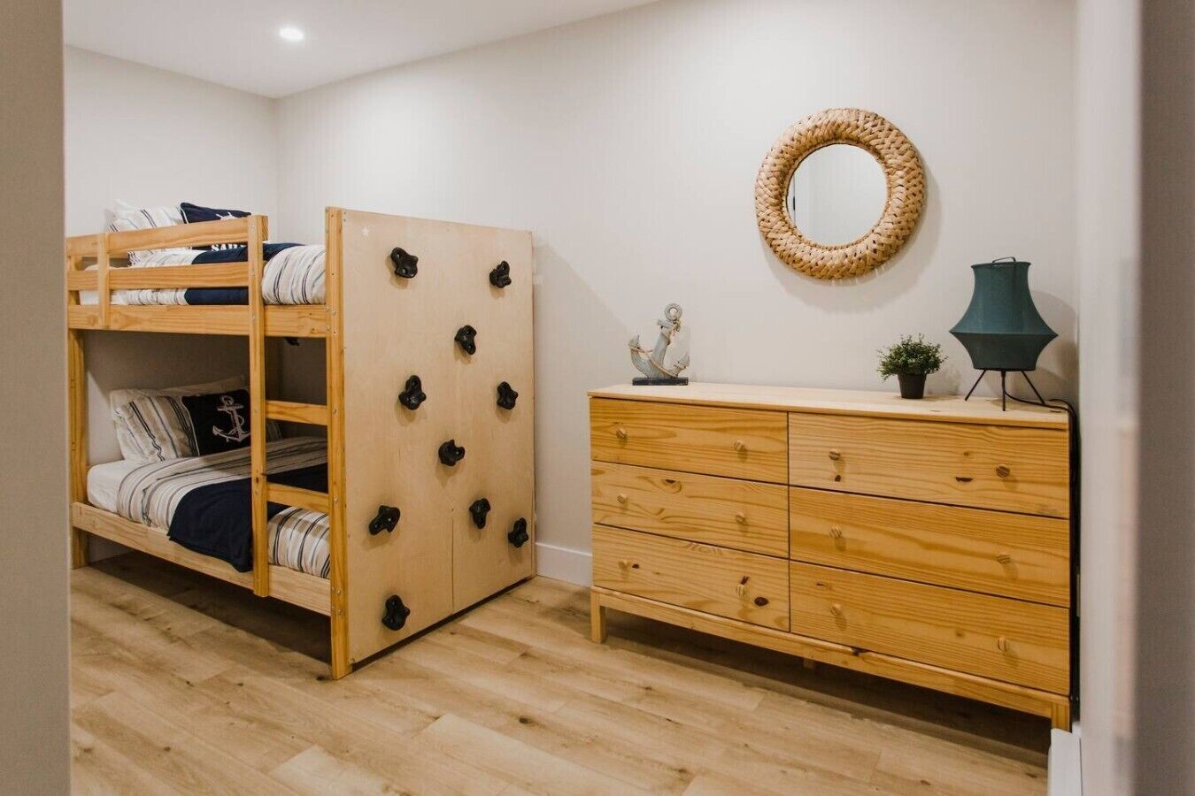 A room with a bunk bed, a wooden dresser, a mirror, and a lamp.