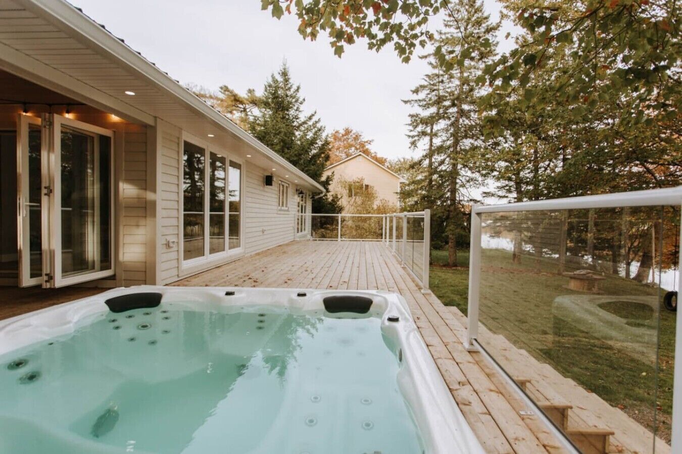 A hot tub on a wooden deck with a house in the background.