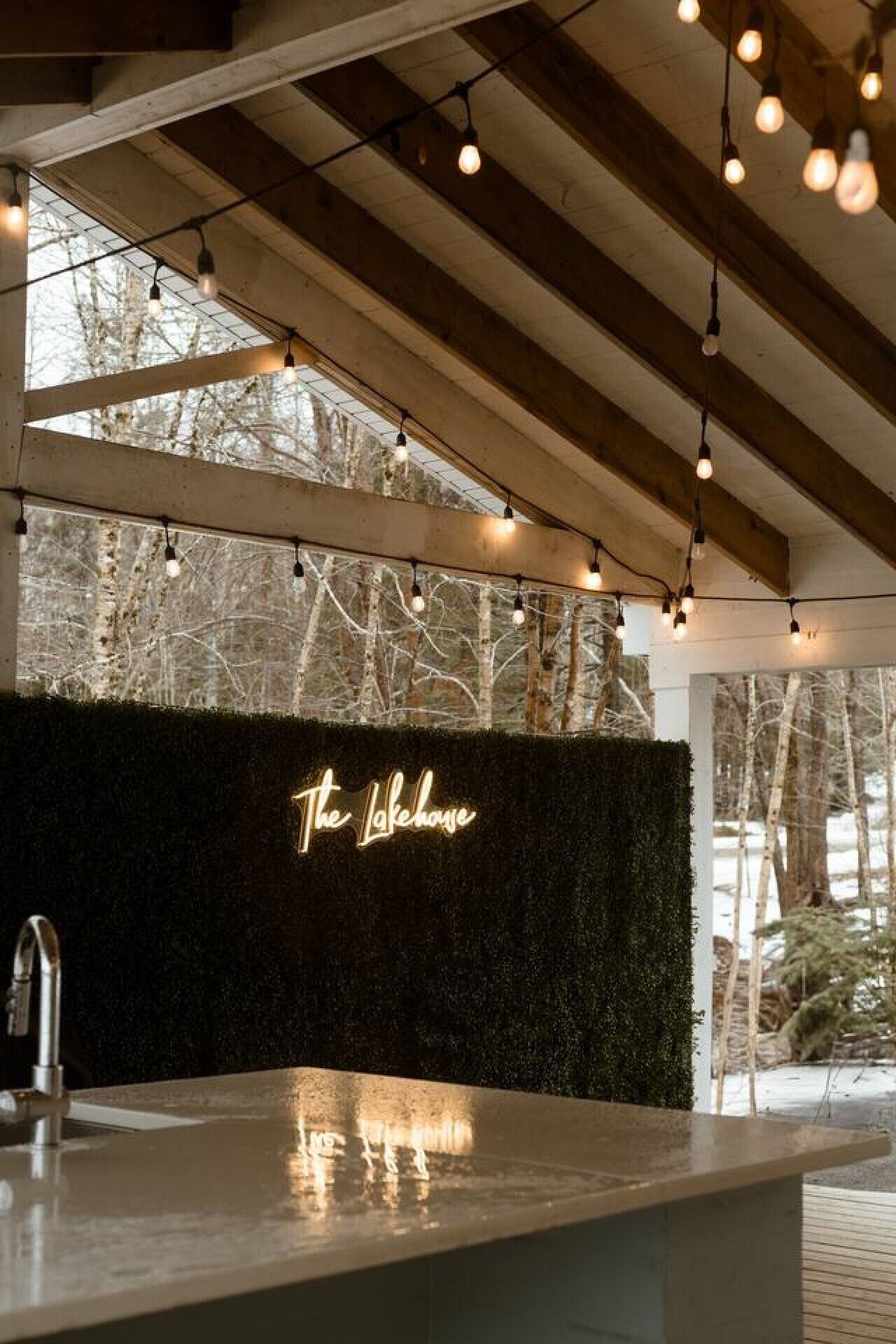 A modern kitchen with a black wall and a neon sign that reads 'The Lakehouse.'