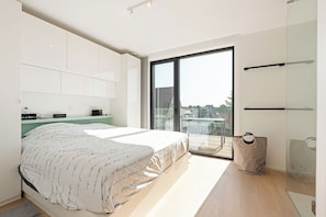 Ein modernes Schlafzimmer mit einem Bett, einem Schreibtisch, einem Stuhl und einem großen Fenster.