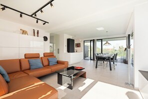 Ein modernes Wohnzimmer mit Sofa, Couchtisch und Essbereich mit Stühlen.
