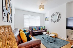 A living room with a sofa, a coffee table, a TV, and a decorative wall piece. - 2 Bed Bungalow| Parking| Garden Leigh-on-Sea (Southend-on-Sea)