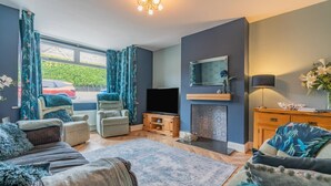 A living room with a fireplace, a television, and a sofa. - 4 Bed in Whitby (oc-w42084) (Whitby)
