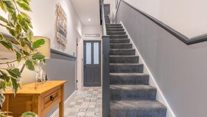 A staircase with carpeted steps, a wooden desk with a lamp, patterned floor tiles, and a door with a sign above it. - 4 Bed in Whitby (oc-w42084) (Whitby)