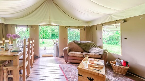 A tented room with a wooden table, chairs, a sofa, and a window overlooking greenery. - 3 Bed in Arley (oc-s42696) (Pound Green)