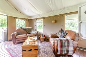 Una habitación con carpa, sofás de cuero, una mesa de centro de madera y una alfombra estampada.