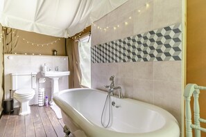 Un baño con bañera, inodoro, lavabo y un salpicadero de azulejos geométricos.