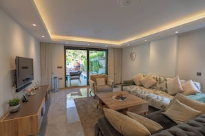 A modern living room with a sofa, coffee table, TV, and a view of the outdoors.