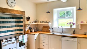 Eine Küche mit Herd, Backofen, Spüle und Fenster.