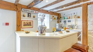 Un coin bar avec une enseigne indiquant « HIGHBURY N.5 », une horloge, ainsi que diverses bouteilles et verres.