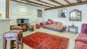 Un salon chaleureux avec un mur en pierre, une cheminée, un canapé, un tapis et un plafond en bois.