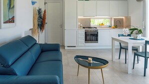 Et moderne køkken med hvide skabe, et spisebord med stole, en sofa og et sofabord.