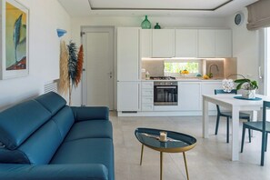 Eine moderne Küche mit weißen Schränken, einem Esstisch mit Stühlen, einem Sofa und einem Couchtisch.