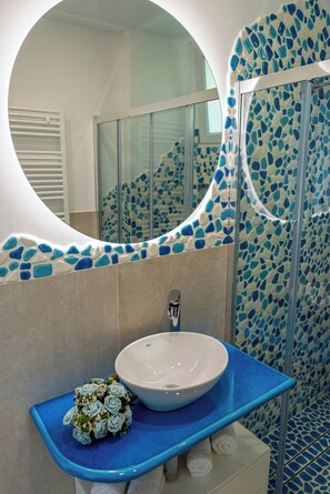 Ein Badezimmer mit einem weißen Waschbecken, einer blauen Arbeitsplatte und mosaikbesetzten Wänden.