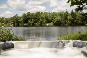 A hot tub with a view of a lake surrounded by trees. - The Lily Pad - Charming Lakefront w/ Hot tub (Mount Uniacke)
