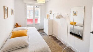 Et soveværelse med seng, kommode, spejl og et vindue med udsigt.