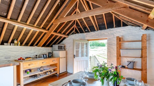 Una cocina estilo ático con vigas de madera, una mesa de comedor para cuatro personas y vistas al exterior.