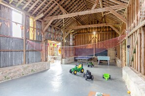 A spacious barn interior with wooden beams, a ping pong table, and toy tractors.