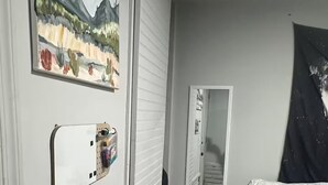 Et soveværelse med en seng, et maleri, et spejl og en dør.