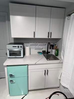 A compact kitchen with white cabinets, a built-in oven, a sink, and a small teal refrigerator. - Private Studio in Downtown Phoenix, 5mins from downtown, sports games, airport! (Phoenix)
