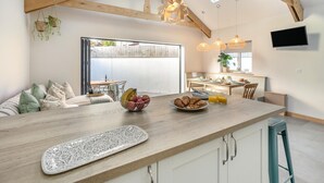 A modern kitchen with wooden beams, a breakfast bar, and a dining area with a view. - 3 Bed in Falmouth (oc-o42451) (Falmouth)