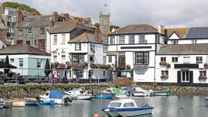 A harbor with boats docked, a white building with black shutters, and a stone tower in the background. - 3 Bed in Falmouth (oc-o42451) (Falmouth)