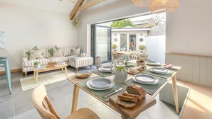 A dining area with a table set for four, a sofa, and a view of the outside. - 3 Bed in Falmouth (oc-o42451) (Falmouth)