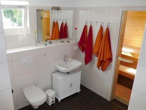 Ett badrum med toalett, handfat, spegel och en duschavdelning med träpanel.