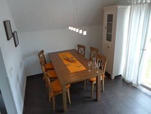 En matplats med ett träbord, sex stolar, en kristallkrona och ett skåp.