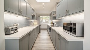 A narrow kitchen with grey cabinets, a toaster, a sink, and a microwave. - 5 Bed in Machrie (oc-h42798) (Machrie)
