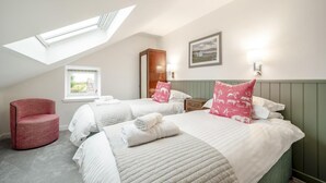 A room with two beds, a red chair, a skylight, a window, and a painting on the wall. - 5 Bed in Machrie (oc-h42798) (Machrie)