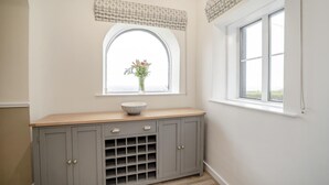 A room with a window, a wooden bench, a cabinet with drawers, and a vase with flowers. - 5 Bed in Machrie (oc-h42798) (Machrie)