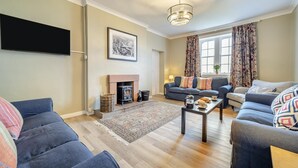 A living room with a fireplace, sofas, a coffee table, and a television. - 5 Bed in Machrie (oc-h42798) (Machrie)