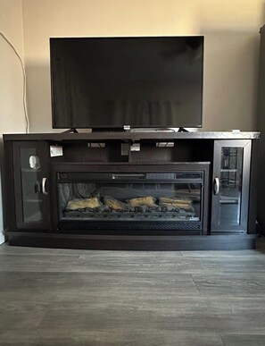 Un mueble multimedia negro con un televisor de pantalla plana en la parte superior y una chimenea empotrada debajo.