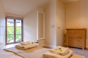 A bedroom with a bed, a window with a view, a wooden dresser, and a door. - 3 Bed in Lanreath (oc-j42768) (Lanreath)