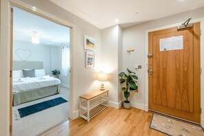 Ein Schlafzimmer mit Bett, Nachttisch, Lampe und einer Zimmerpflanze.