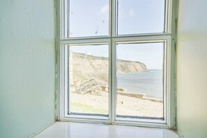 Ein Fenster mit Blick auf einen Strand, Klippen und einen Zaun.