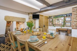 Ein Holztisch mit Frühstücksangeboten, eine Ziegelwand und ein an der Wand befestigter Fernseher.