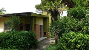 Un edificio con fachada verde, sección de ladrillo y una ventana pequeña.