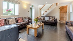 A modern living room with leather sofas, a wooden coffee table, and a staircase leading to another level. - 6 Bed in Llansantffraid (oc-r42827) (Llansantffraid)