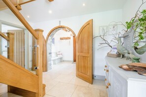 A wooden staircase leading to a room with a white door, a bench, and decorative items. - 3 Bed in Marhamchurch (oc-h29904) (Marhamchurch)