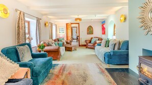 A cozy living room with a fireplace, leather sofas, and a large rug. - 5 Bed in Hayle (oc-r42756) (Saint Erth Praze)