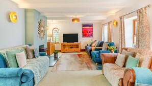 A living room with a TV, sofas, a coffee table, and a fireplace. - 5 Bed in Hayle (oc-r42756) (Saint Erth Praze)