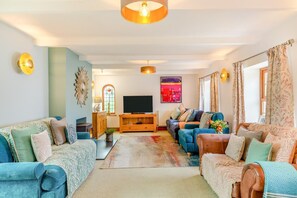 Ein Wohnzimmer mit Fernseher, Sofas, einem Couchtisch und einem Kamin.