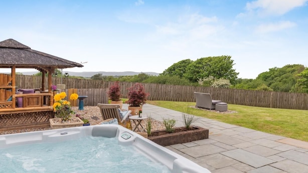 A backyard with a hot tub, outdoor seating, and a wooden deck. - 5 Bed in Hayle (oc-r42756) (Saint Erth Praze)